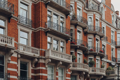 Exterior of a traditional red brick apartment block with balconies in kensington, london, uk.