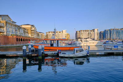 Boats moored in river against buildings in city