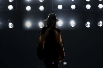 Rear view of woman standing against illuminated lights