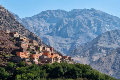 Scenic view of townscape by mountains against sky