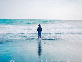 Rear view of man on beach against sky