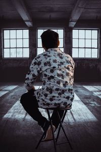 Rear view of woman sitting on floor at home