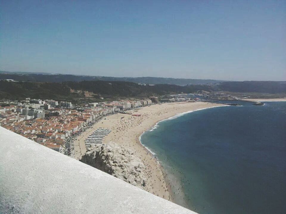 sea, beach, clear sky, built structure, water, architecture, copy space, building exterior, high angle view, coastline, sand, shore, blue, cityscape, scenics, horizon over water, city, town, nature, day