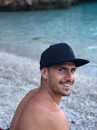 Portrait of shirtless man wearing cap at beach