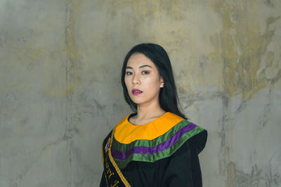 Portrait of woman standing against wall