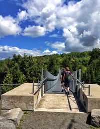 People on railing against cloudy sky