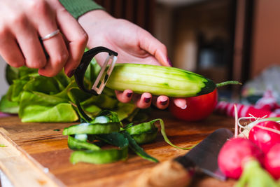 Cropped hands of person holding vegetables on cutting board