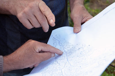 Cropped image of people discussing over map outdoors