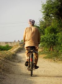 Rear view of man riding bicycle on road