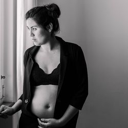 Portrait of beautiful young woman standing against wall at home