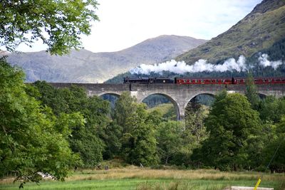 Arch bridge over mountains against sky