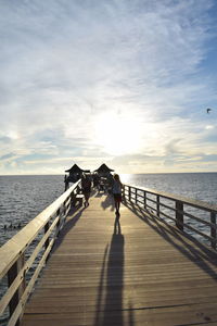 People on pier over sea against sky