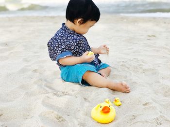 Boy playing with toy on sand at beach