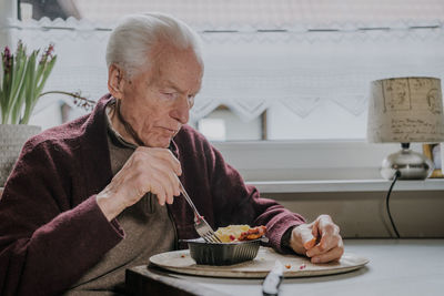 Senior man eating food at home