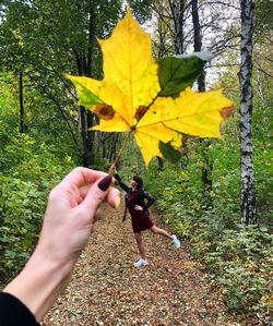 Midsection of person on yellow leaves during autumn