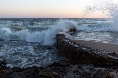 Waves splashing on shore against sky