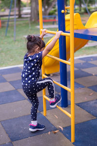 Side view of girl moving up on ladder at playground