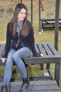 Full length of woman sitting on bench in park