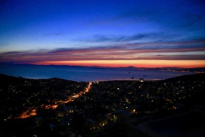 Aerial view of illuminated city against sky at sunset