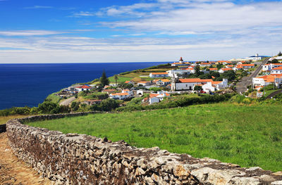 Scenic view of town by sea against sky