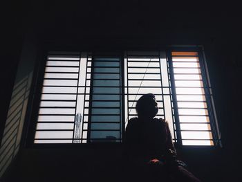 Silhouette of man standing against window