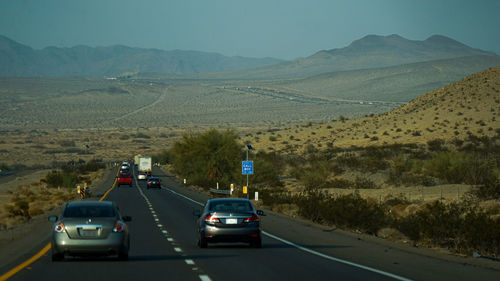 Cars on road by mountains against sky
