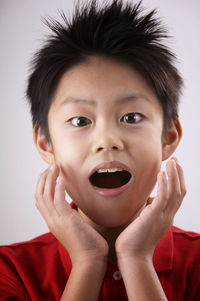 Close-up of surprised boy against white background