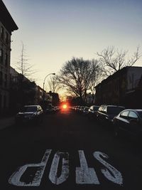 Road passing through city during sunset