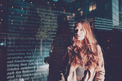 Young woman standing against glass wall