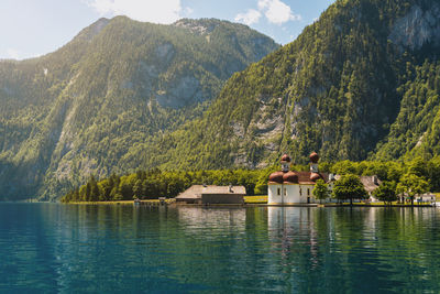 People by swimming pool by lake against mountains
