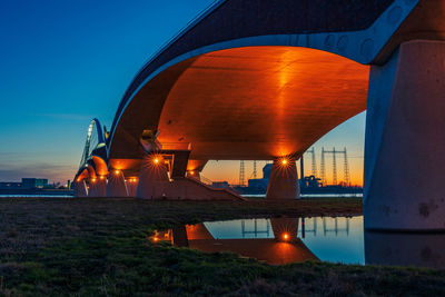 The de oversteek bridge in the dutch city of nijmegen is illuminated in the evening.