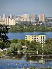 Buildings by river against sky