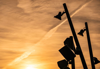 Dramatic evening sky in front of stands and poles with loudspeakers and cameras.