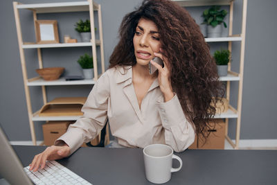 Young woman using mobile phone while sitting in cafe