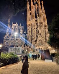 People at illuminated temple outside building against sky at night