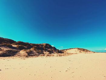 Scenic view of desert against clear blue sky