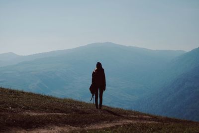 Rear view of woman looking at mountains against sky