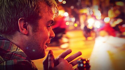 Close-up of man smiling in city at night