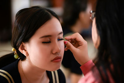 Close-up of young woman applying make-up at home