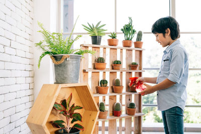 Side view of man standing by potted plants