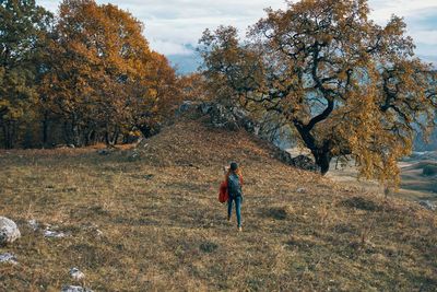 Rear view of man walking on field during autumn