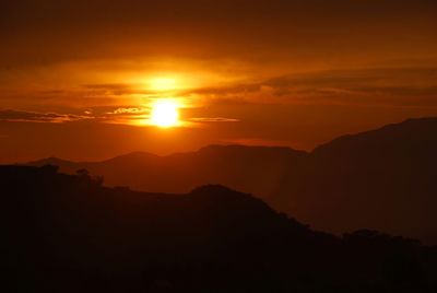 Scenic view of silhouette mountains against romantic sky at sunset