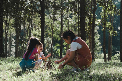 Mother setting bonfire with kids at forest