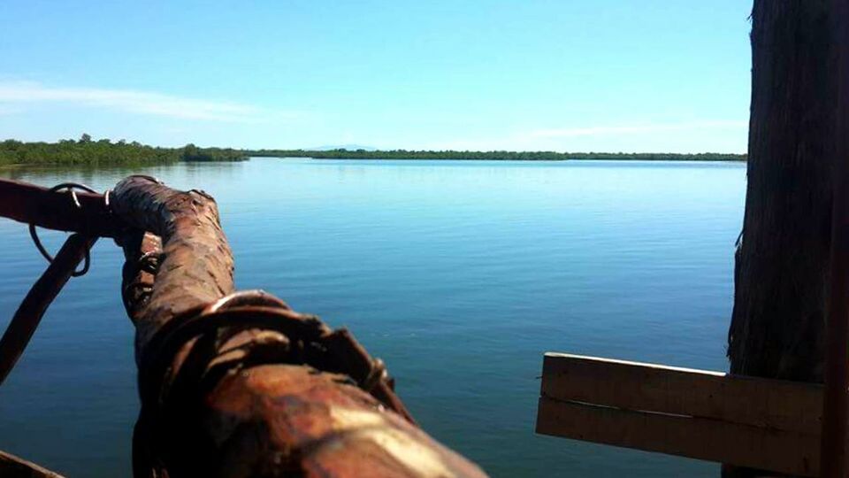 LOW SECTION OF MAN SITTING ON WOODEN POST IN LAKE