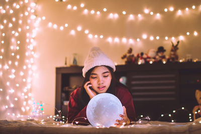 Smiling woman with crystal ball at illuminated home during christmas