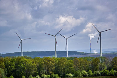 Wind turbines on field against sky