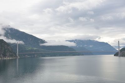 View of suspension bridge over river against cloudy sky