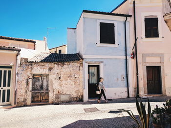 Man standing outside house against sky