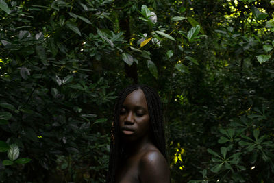 Close-up of shirtless young woman against trees