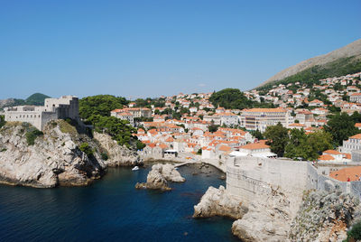 Townscape by sea against clear blue sky